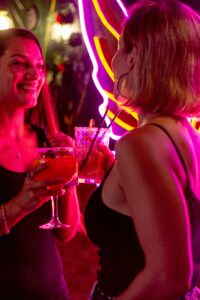 ネオンライトが輝くバーでカクテルを楽しむ女性たち