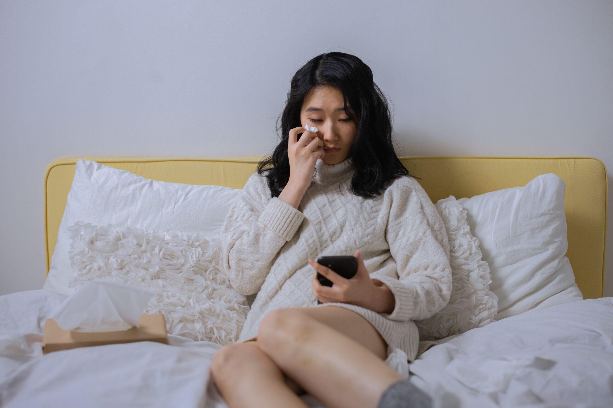 スマホを見つめて涙を拭う女性のイメージ